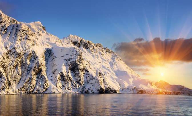De schijnende zon die tussen de ijzige rotsen doorkomt