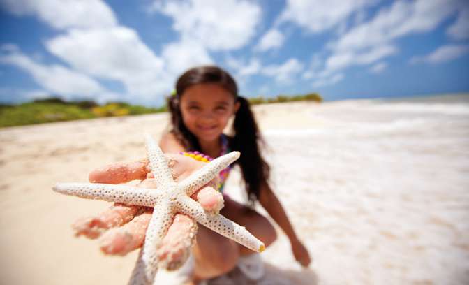 Kind met zeester op het strand 