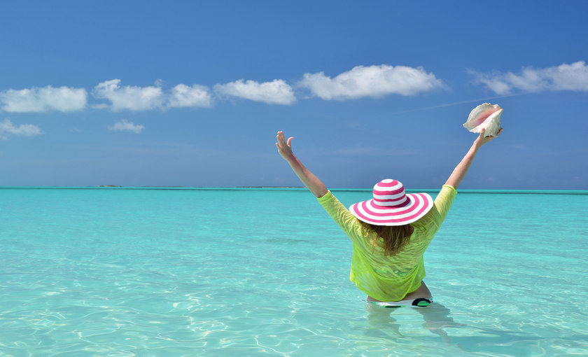 Een vrouw met zonnehoed in de zee bij de Bahamas